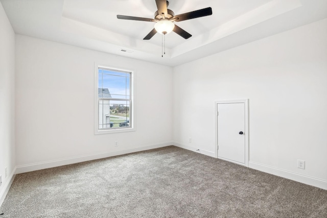 spare room with carpet, a raised ceiling, and ceiling fan