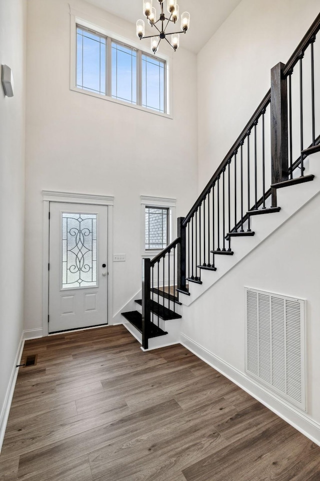 entryway featuring hardwood / wood-style flooring, a notable chandelier, and a towering ceiling