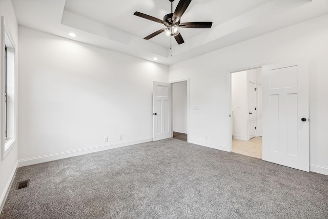 unfurnished bedroom with a tray ceiling, ceiling fan, and light carpet