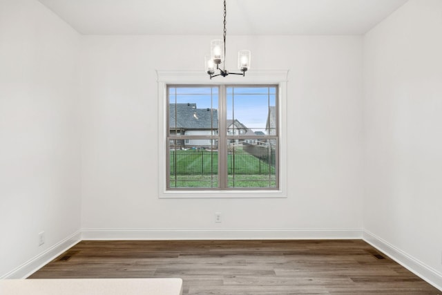 unfurnished dining area with wood-type flooring and a chandelier