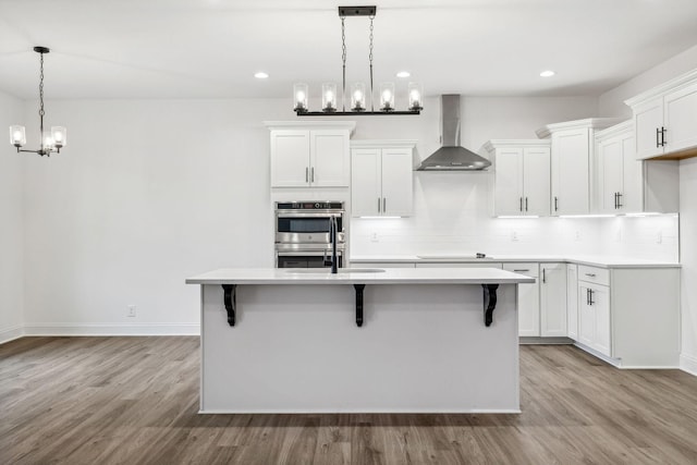 kitchen featuring light hardwood / wood-style floors, wall chimney range hood, and white cabinetry