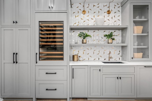 bar featuring tasteful backsplash, wine cooler, sink, and hanging light fixtures