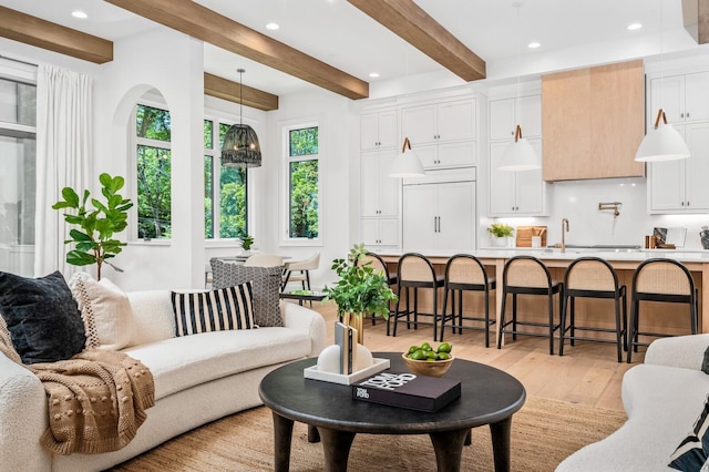 living room featuring sink, beamed ceiling, and light hardwood / wood-style floors