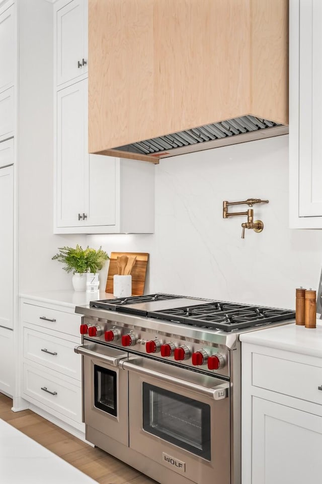 kitchen with light hardwood / wood-style flooring, double oven range, and white cabinetry