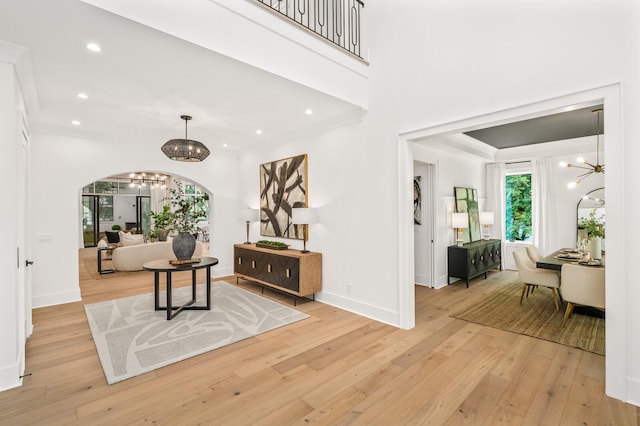 foyer entrance with light hardwood / wood-style flooring, ornamental molding, and a notable chandelier