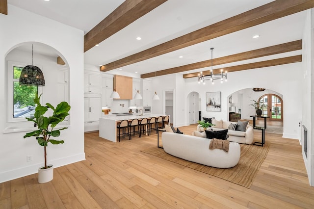 living room featuring beam ceiling, light wood-type flooring, and a chandelier