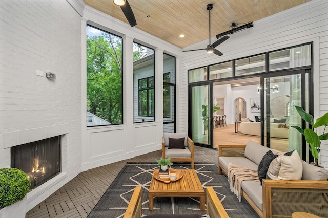 sunroom / solarium featuring ceiling fan, wood ceiling, and a brick fireplace