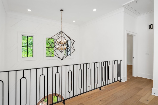 hall with an inviting chandelier, wood-type flooring, and ornamental molding