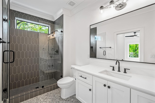 bathroom with ornamental molding, vanity, ceiling fan, toilet, and a shower with shower door