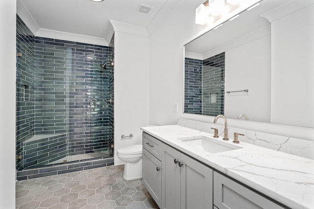 bathroom with vanity, tile patterned flooring, toilet, ornamental molding, and tiled shower