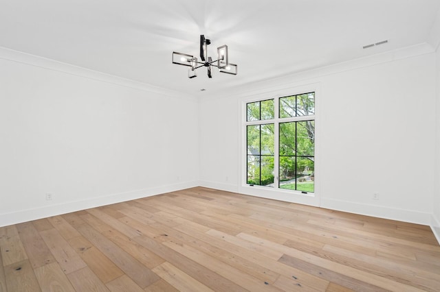 empty room with light hardwood / wood-style floors, an inviting chandelier, and ornamental molding