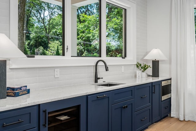 bar featuring decorative backsplash, a healthy amount of sunlight, and sink