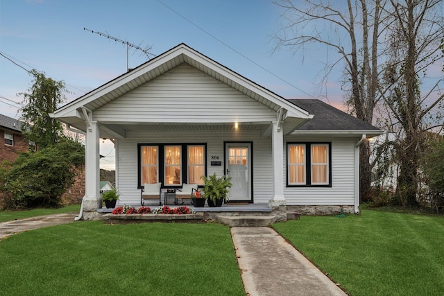 bungalow featuring a porch and a lawn