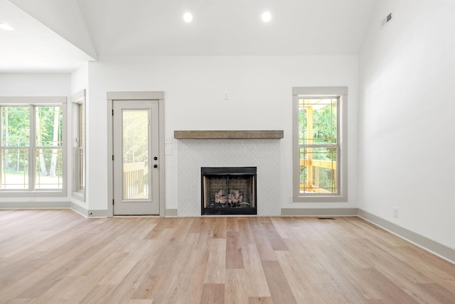 unfurnished living room featuring light hardwood / wood-style flooring, vaulted ceiling, and plenty of natural light