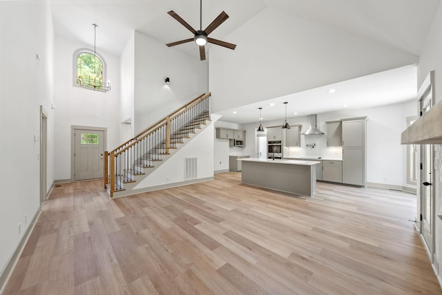 unfurnished living room featuring light wood-type flooring, high vaulted ceiling, and a healthy amount of sunlight