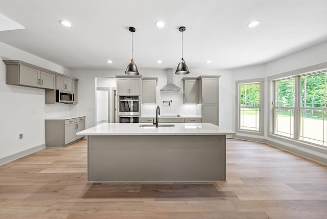 kitchen with sink, wall chimney exhaust hood, stainless steel appliances, and light hardwood / wood-style floors