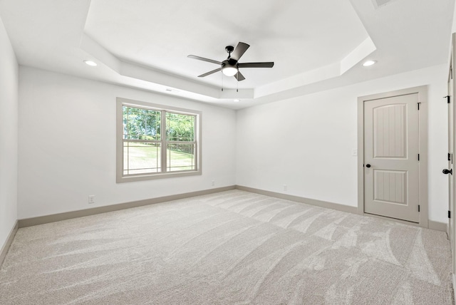 empty room featuring a tray ceiling and light carpet