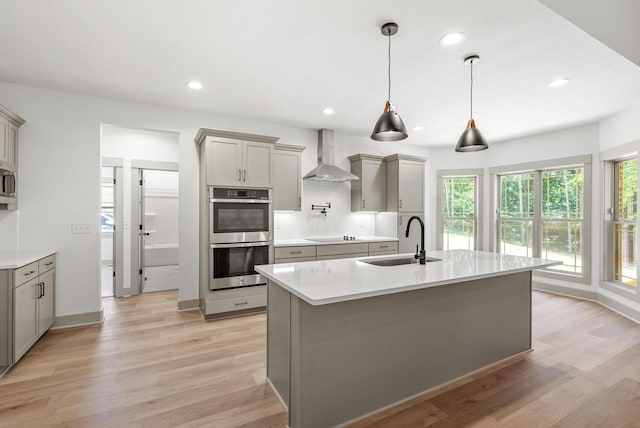 kitchen featuring stainless steel appliances, plenty of natural light, wall chimney exhaust hood, and sink