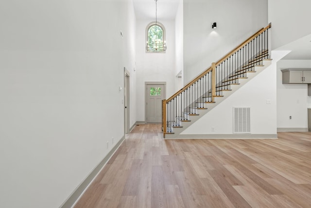 entryway featuring a high ceiling, light wood-type flooring, and an inviting chandelier