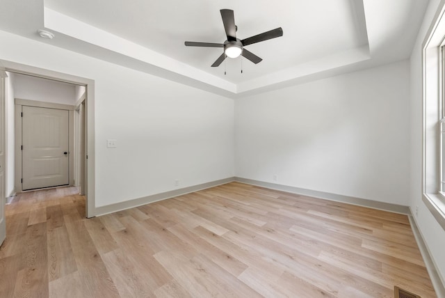 unfurnished room with ceiling fan, light hardwood / wood-style floors, and a raised ceiling