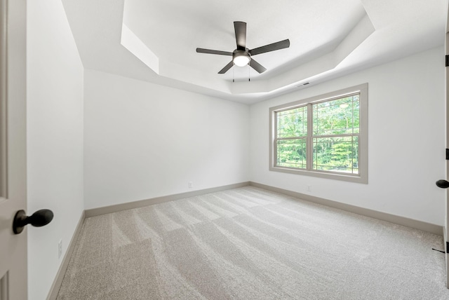 spare room with light carpet, a raised ceiling, and ceiling fan