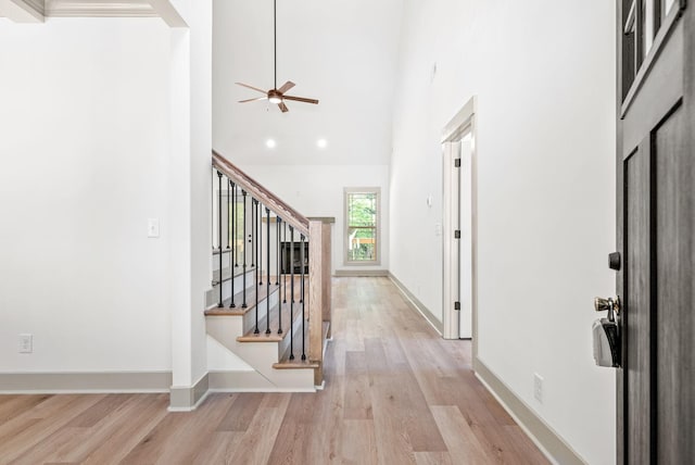 entryway featuring ceiling fan, light hardwood / wood-style floors, and a high ceiling