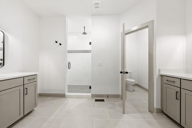 bathroom featuring tile patterned floors, vanity, a shower with shower door, and toilet