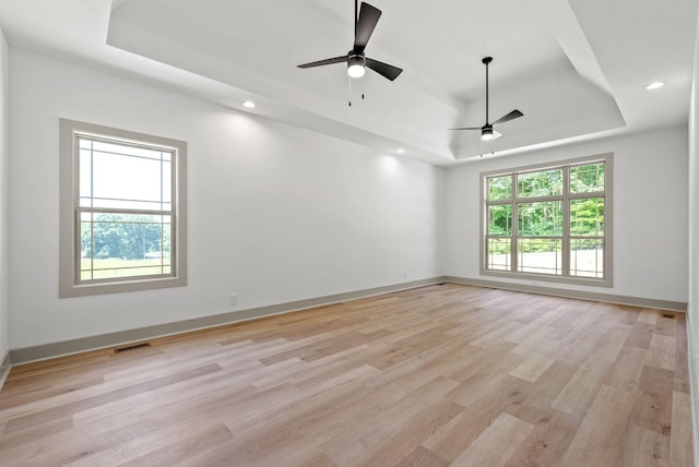 spare room with a raised ceiling, ceiling fan, and light hardwood / wood-style floors