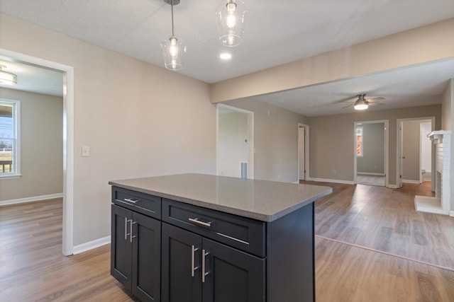 kitchen with ceiling fan, a kitchen island, hanging light fixtures, and light wood-type flooring