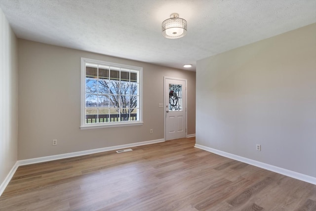 spare room featuring light hardwood / wood-style flooring and a textured ceiling