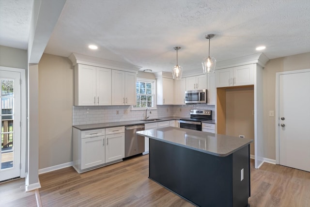 kitchen featuring white cabinetry, a center island, stainless steel appliances, and decorative light fixtures