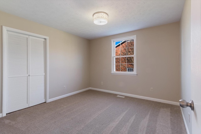 unfurnished bedroom with carpet, a textured ceiling, and a closet