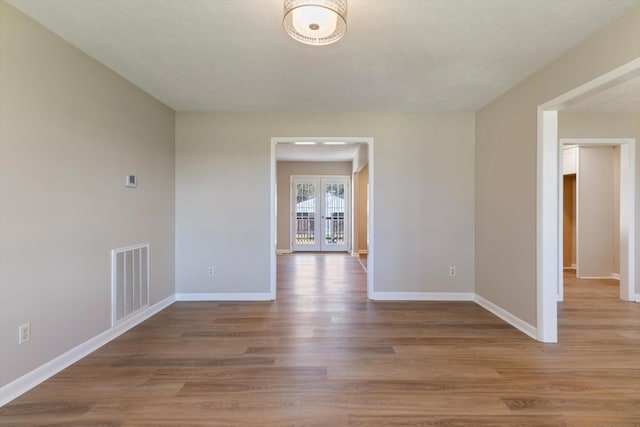 unfurnished room with french doors and light hardwood / wood-style flooring