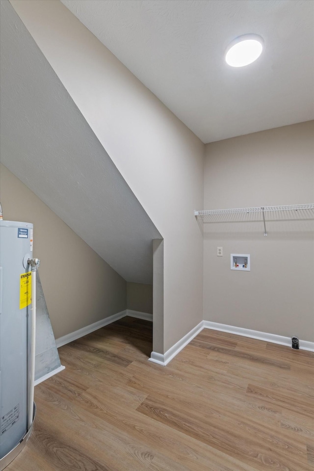 washroom with light wood-type flooring, hookup for a washing machine, and water heater