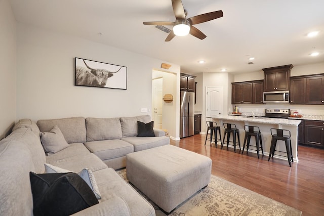 living room featuring ceiling fan, dark wood-type flooring, and sink