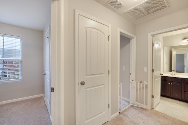 corridor with light colored carpet and sink