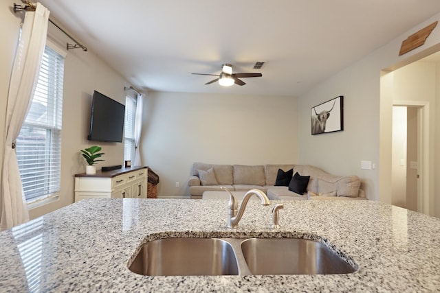 kitchen featuring light stone countertops, ceiling fan, and sink