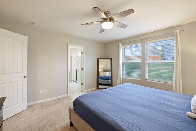 bedroom featuring connected bathroom, light colored carpet, and ceiling fan