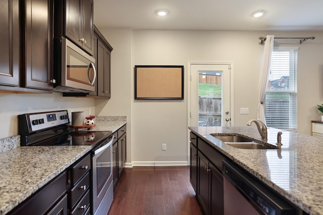 kitchen with sink, dark hardwood / wood-style flooring, light stone counters, dark brown cabinets, and stainless steel appliances