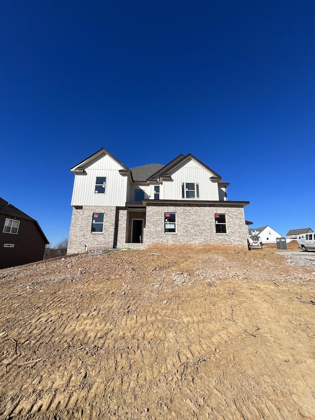 rear view of property with brick siding and board and batten siding