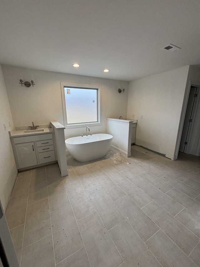 bathroom with a freestanding tub, visible vents, recessed lighting, and vanity