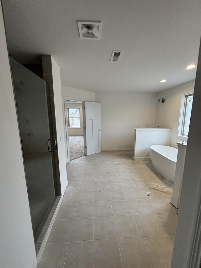 bathroom featuring visible vents, a freestanding bath, and a shower stall