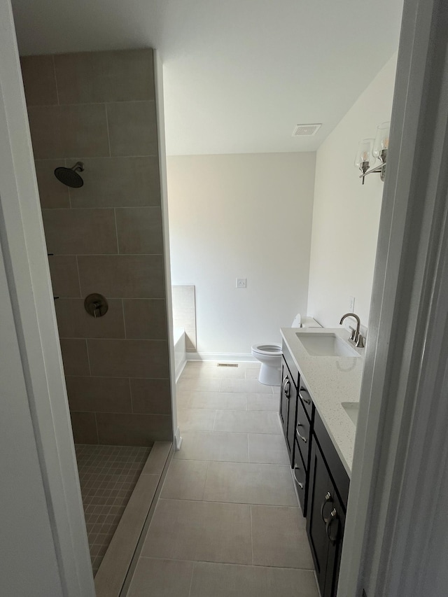 full bathroom with tiled shower, double vanity, a sink, tile patterned flooring, and toilet