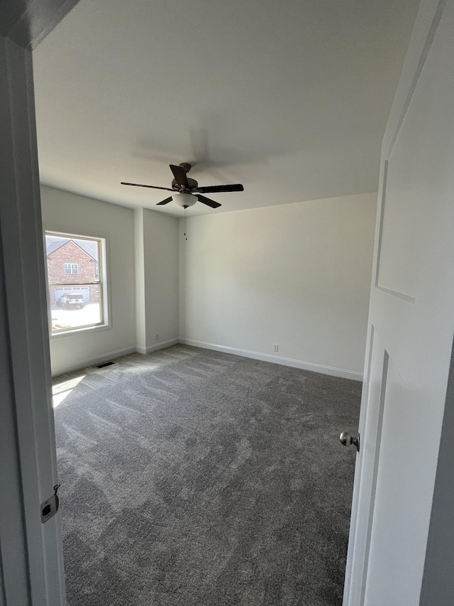 carpeted empty room with visible vents, baseboards, and a ceiling fan