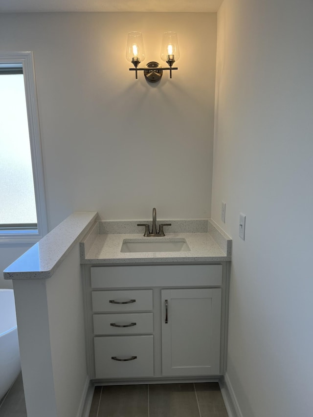 bathroom featuring tile patterned flooring, a freestanding bath, vanity, and baseboards