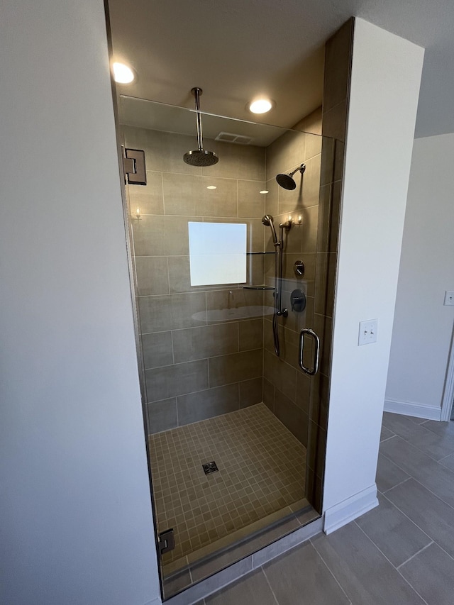 full bath with tile patterned flooring, visible vents, a stall shower, and baseboards