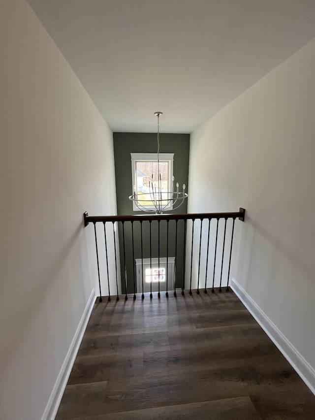 stairway with baseboards, an inviting chandelier, and wood finished floors