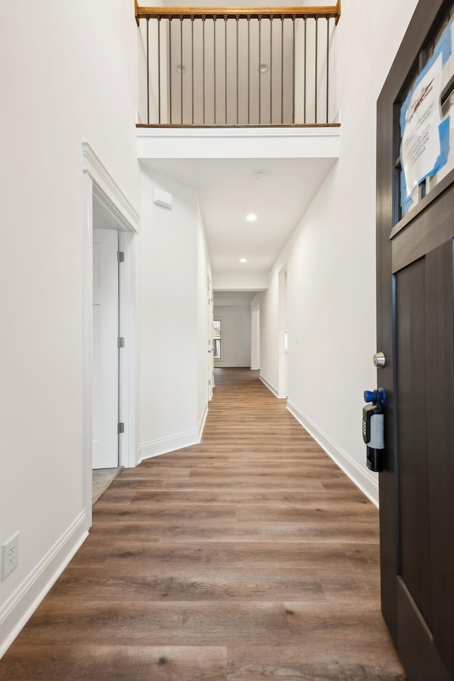 corridor featuring baseboards, wood finished floors, and recessed lighting