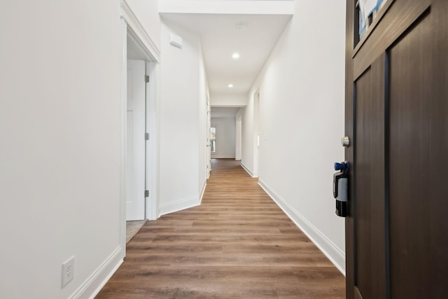 hall featuring baseboards, light wood-style floors, and recessed lighting