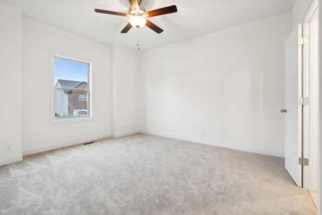 spare room with baseboards, ceiling fan, visible vents, and light carpet